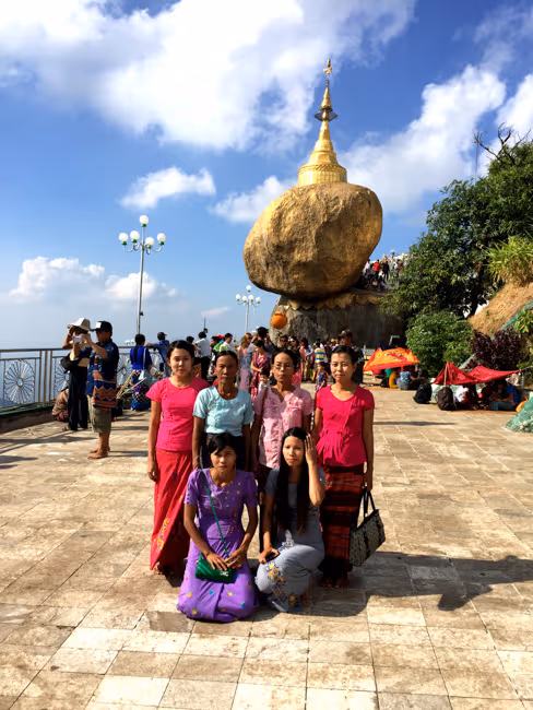 Familia birmana tomándose una foto de grupo con la Roca Dorada detrás, en el monte Kyaiktiyo