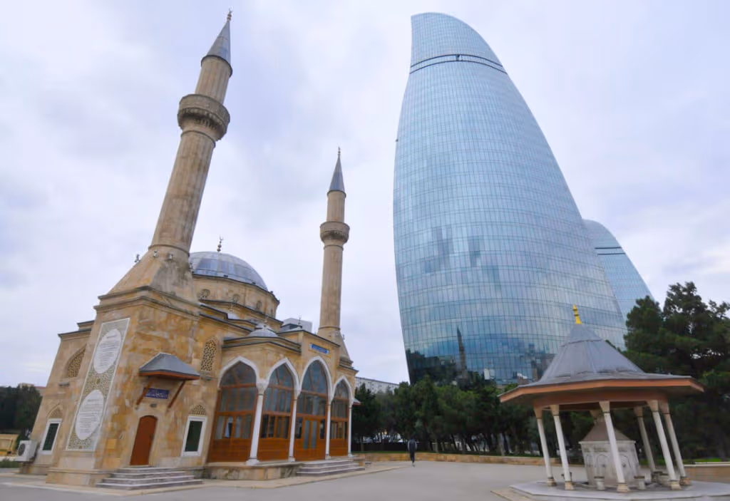 Una mezquita y las recientes construidas torres llama en Baku